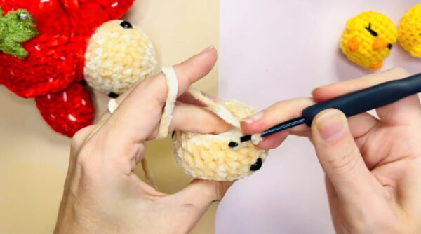 Crocheting cream stitches on strawberry doll head
