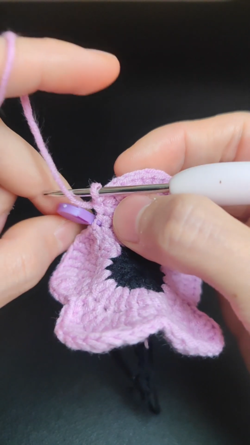 Crocheting pink flower petal with hook