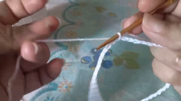 Hand working a foundation chain with white yarn