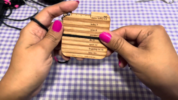 Checking yarn weight with wooden gauge