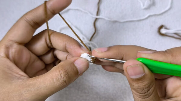 Crocheting brown ear piece with green hook