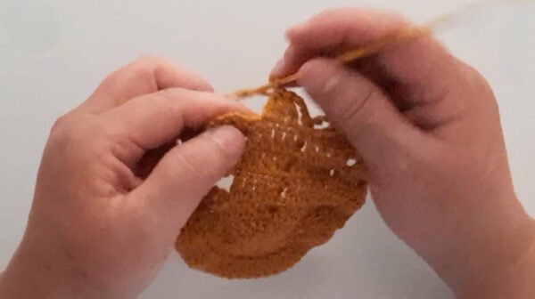 Crocheting brown edge on colorful patchwork blanket