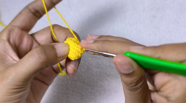 Crocheting round 5 of yellow amigurumi piece