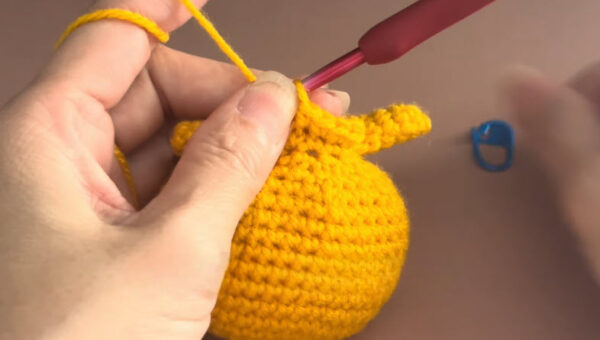 Crocheting yellow amigurumi body with hook