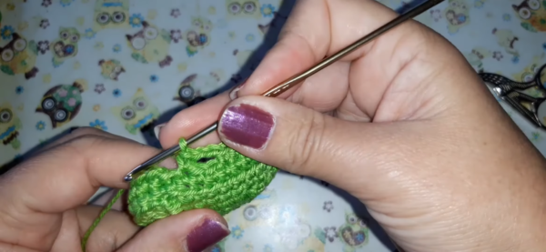 Fitting earbuds inside green crochet case