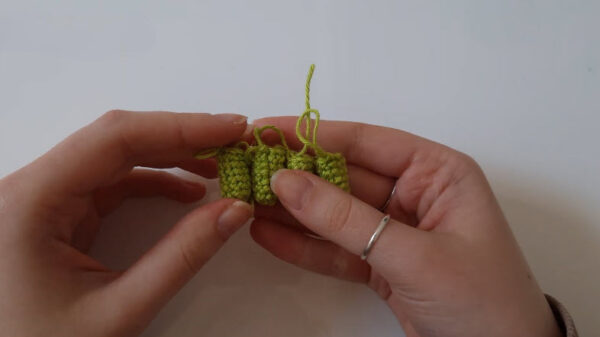 Four small green crochet legs lined up side by side.