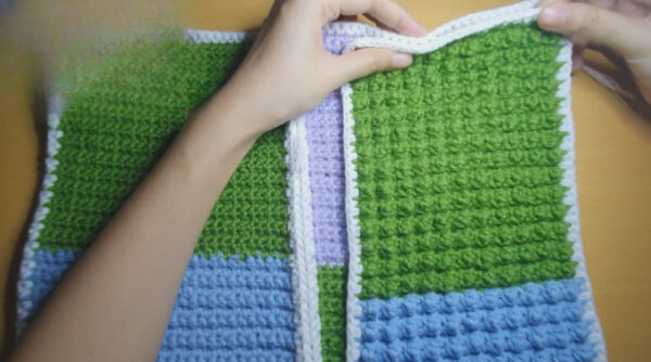 Green, blue, and purple crochet blocks forming a cardigan front.