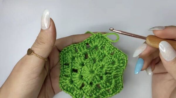 Green crochet hexagon granny square held in hand.Green crochet hexagon granny square held in hand.