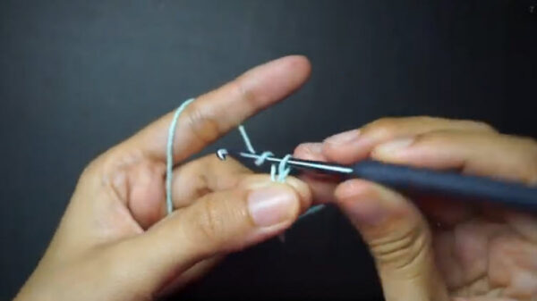 Hands starting a foundation chain with mint crochet thread.