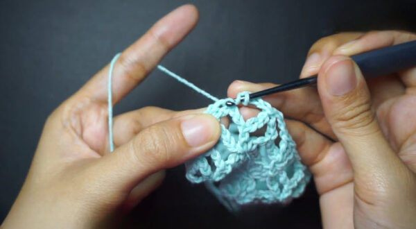 Hook continuing mesh stitch rows on mint crochet piece.