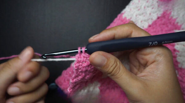 Hook decreasing stitches in pink checkered crochet pattern.