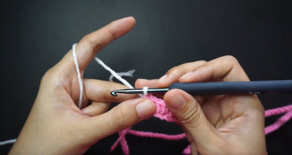 Hook working lemon peel stitch with white and pink yarn.