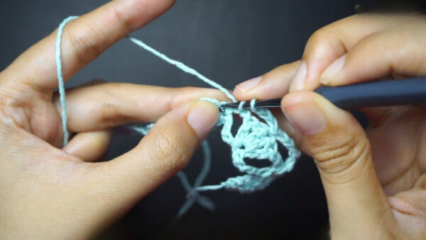 Hook working mesh stitch pattern with mint crochet thread.