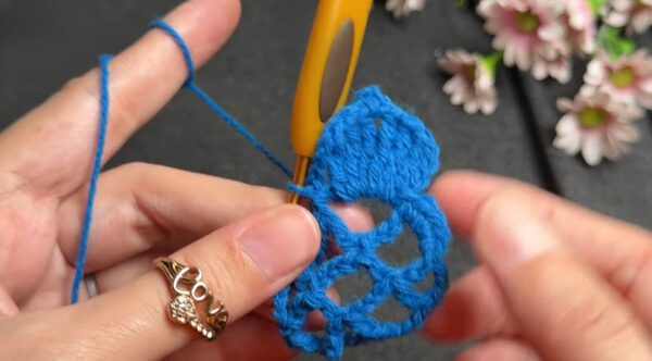 Lace petal motif taking shape in blue crochet