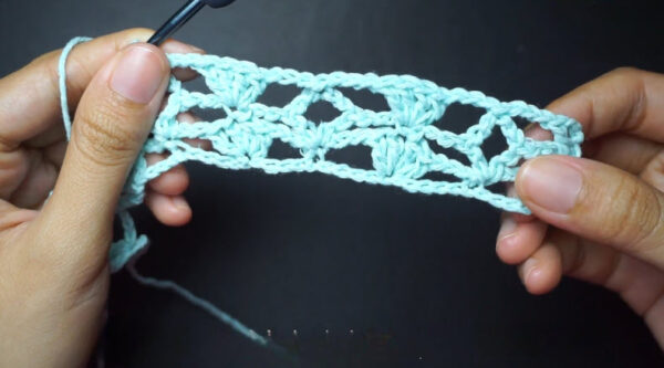 Mint crochet mesh panel held open showing lacy pattern.
