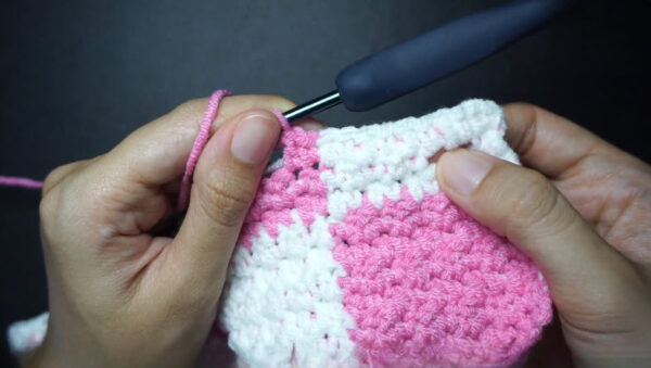 Pink and white checkered crochet fabric with hook joining colors.
