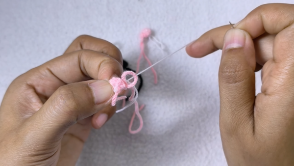 Stitching pink details on amigurumi monkey piece