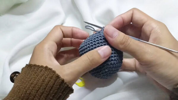 Stuffing the gray koala head piece with polyester fiberfill.