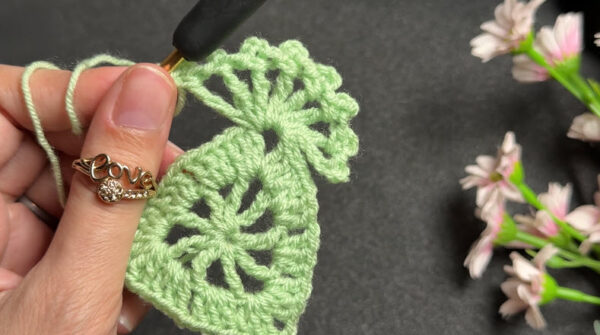Working edge stitches on green crochet motif