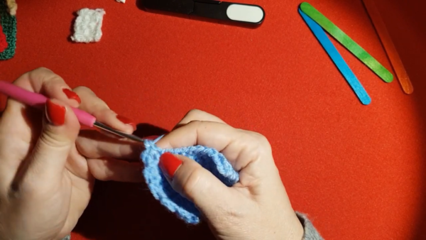 Working rounds on blue crochet house shape
