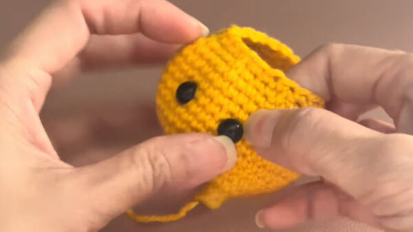 Yellow amigurumi head with black safety eyes