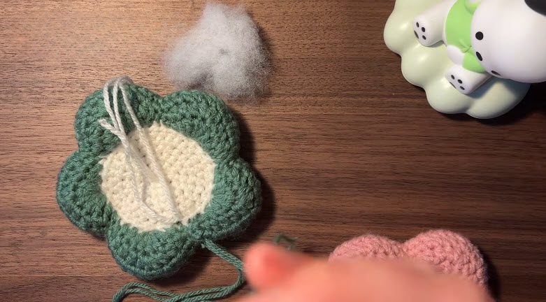 Add stuffing before closing the flower in the crochet flower coasters pattern.