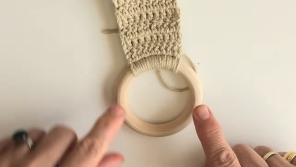 Beige crochet strap stitched to a wooden towel ring