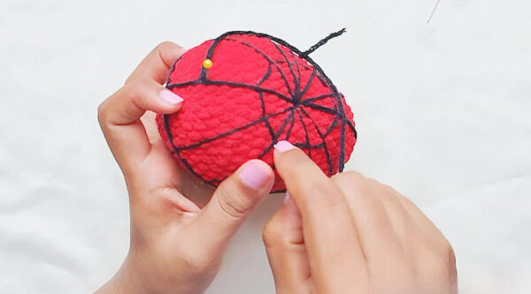 Crochet Spider-Man keychain detail: black spider web pattern stitched over the red head