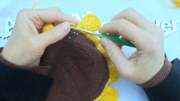 Crocheting yellow petals around the sunflower wall pocket