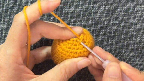 Final decrease round closes the body of the crochet chick in a hat keychain