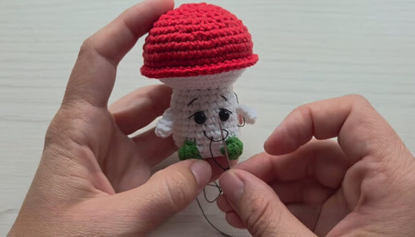 Finished crochet mushroom keychain with black eyes and a stitched smile