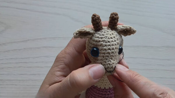Finished tan crochet head with brown horns, ears and a stitched mouth.