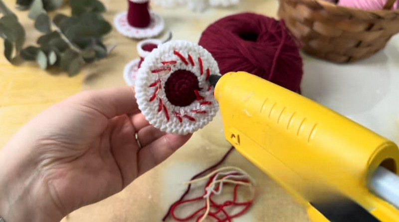 Gluing the white felt circle under the saucer base of the crochet tea glass pattern.