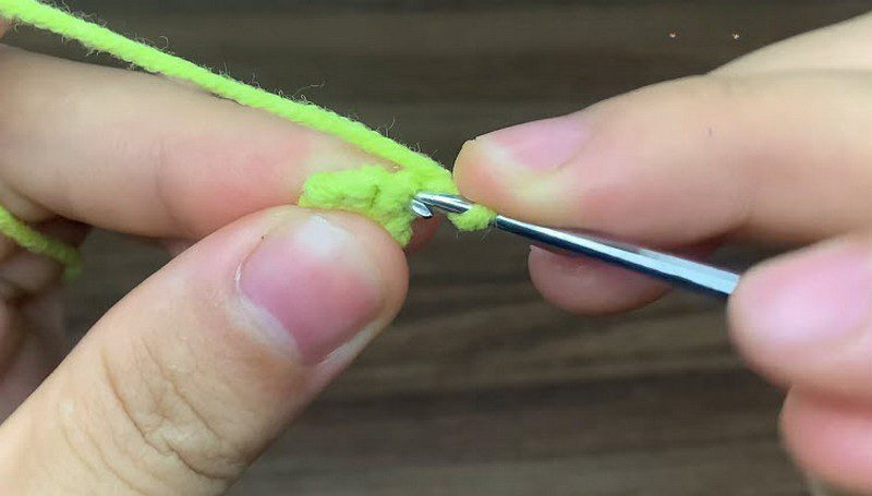 Hook working short rows of green single crochet stitches with an increase.