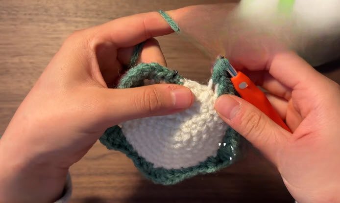Join green yarn and crochet the petal edge of the crochet flower coasters pattern.