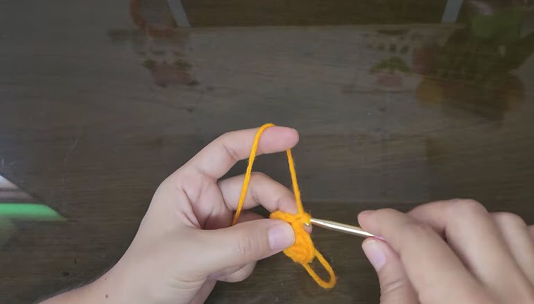 Orange yarn over finger with the first stitches started