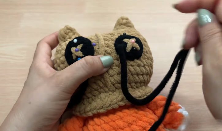 Pin the black eye patches and ears onto the head.