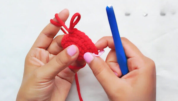 Crochet Spider-Man keychain step: red oval piece taking shape with a loop on top